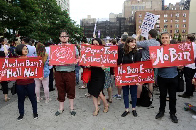 Protesters hold signs against U.S. President Donald Trump's limited travel ban, approved by the U.S. Supreme Court, in New York City, U.S., June 29, 2017.