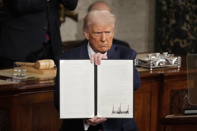 President Donald Trump holds up a signed executive order as he addresses a joint session of Congress at the Capitol in Washington, Tuesday, March 4, 2025.