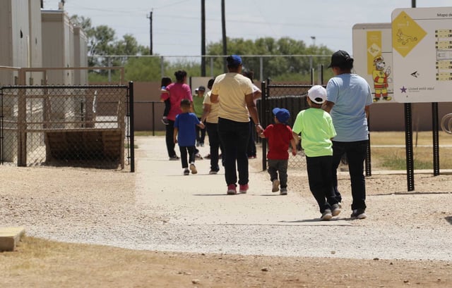 In this Aug. 23, 2019 file photo, immigrants seeking asylum hold hands as they leave a cafeteria at the ICE South Texas Family Residential Center in Dilley, Texas. The isolation of at least three families at the U.S. Immigration and Customs Enforcement&#39;s detention center in Dilley, has raised new fears of the coronavirus spreading through a facility that has long been accused of providing substandard medical care.