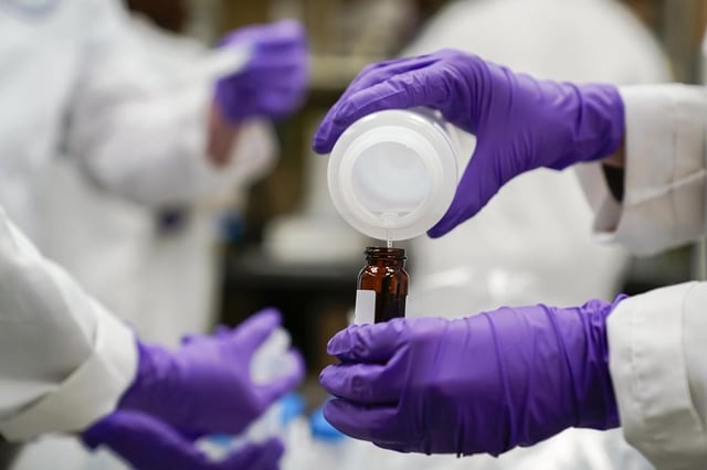 FILE - Eva Stebel, water researcher, pours a water sample into a smaller glass container for experimentation as part of drinking water and PFAS research at the U.S. Environmental Protection Agency Center For Environmental Solutions and Emergency Response, Feb. 16, 2023, in Cincinnati. Twenty-two attorneys general urged a federal court on Wednesday, July 26, to reject a proposed $10.3 billion settlement over contamination of U.S. public drinking water systems with potentially dangerous chemicals, saying it lets manufacturer 3M Co. off too easily. (AP Photo/Joshua A. Bickel, File)