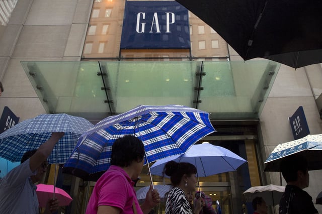 People carrying umbrellas pass by a Gap store on 5th avenue in midtown Manhattan in New York June 16, 2015. REUTERS/Brendan McDermid/File photo