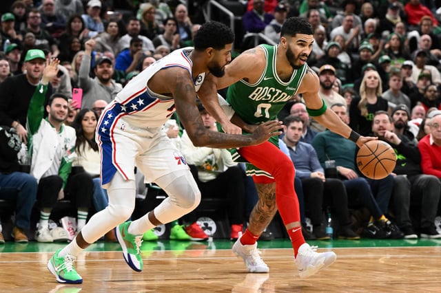 BOSTON, MASSACHUSETTS - DECEMBER 25: Jayson Tatum #0 of the Boston Celtics drives to the basket against Paul George #8 of the Philadelphia 76ers during the fourth quarter at the the TD Garden on December 25, 2024 in Boston, Massachusetts.