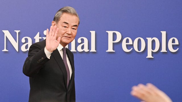 China's Foreign Minister Wang Yi waves as he leaves a press conference during the ongoing National People's Congress (NPC) in Beijing on March 7, 2025. 