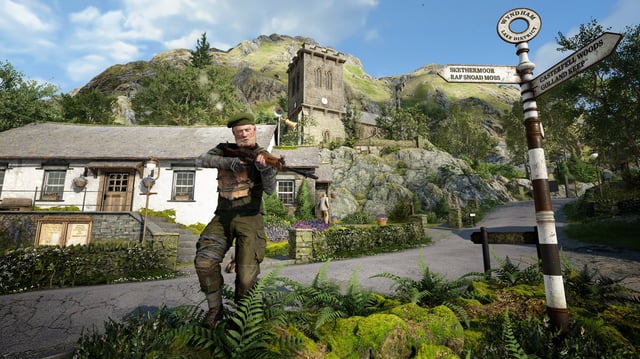 An armed man in a green beret readies his weapon ion a quaint British village.