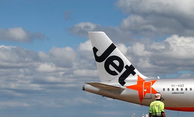 An airport worker is seen with a Jetstar airplane, Airbus A320, at Avalon Airport near Melbourne March 19, 2010. Jetstar Airways is a subsidiary of Qantas Airlines Limited, it is a low-cost airline headquartered in Melbourne, servicing domestic and international routes.