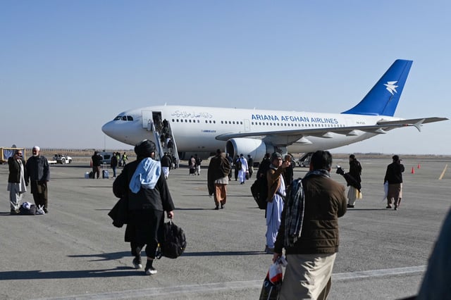 Afghan passengers walk to board an Ariana Afghan Airlines commercial aircraft bound for Kabul, at Khwaja Abdullah Ansari International Airport, in Guzara district, around 10km southeast of Herat on December 23, 2024. (Photo by Wakil Kohsar / AFP) (Photo by WAKIL KOHSAR/AFP via Getty Images)