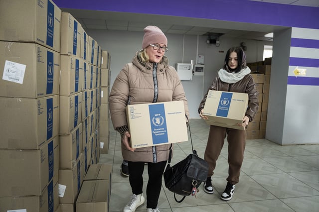FILE - Tetyana Bobina and her daughter Aleksandra receive humanitarian aid provided by UN World Food Program and ADRA charity organisation for the residents of the region and internally displaced persons at the distribution center in Kostiantynivka, Ukraine, Friday, Feb. 10, 2023. (AP Photo/Evgeniy Maloletka, File)
