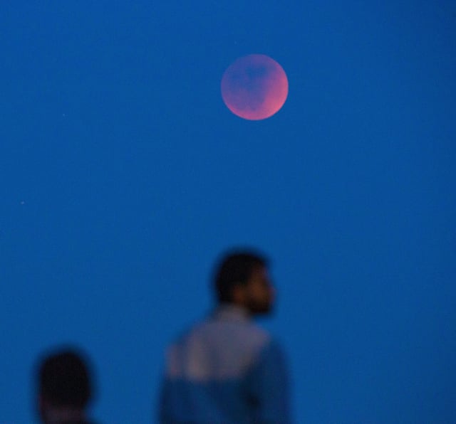 Spectators view a total lunar eclipse in 2022 in Eugene, Oregon. A lunar eclipse occurs when the sun, Earth, and moon align so that the moon passes into Earth's shadow. In a total lunar eclipse, the entire moon falls within the darkest part of Earth's shadow, called the umbra.