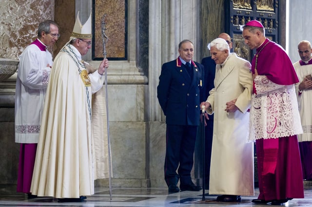 Pope Francis, second from left, watches Pope Emeritus Benedict XVI enter St. Peter's Basilica accompanied by Monsignor Georg Gaenswein, right, at the Vatican, on Dec. 8, 2015. (AP Photo/Andrew Medichini, File)