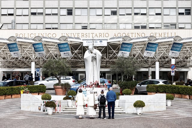 People gather near the statue of late Pope John Paul II outside Gemelli Hospital, where Pope Francis is admitted for treatment, in Rome, Italy, March 8, 2025.