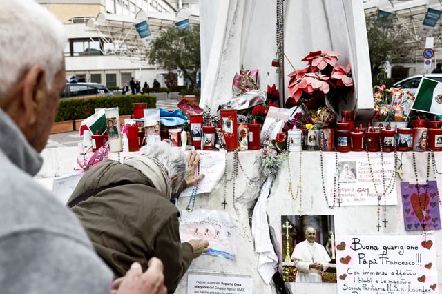 People gather in front of the statue of late Pope John Paul II outside Gemelli Hospital, where Pope Francis is admitted for treatment, in Rome, Italy, March 8, 2025.