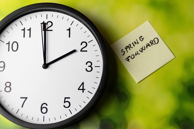 Stock image of a clock with a note to &#39;spring forward&#39;.