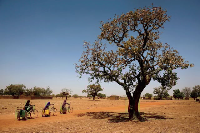 Girls carry water on their bicycles at a dispensary in Nedogo village near Ouagadougou, Burkina Faso, in the African Sahel region, in February 2018.