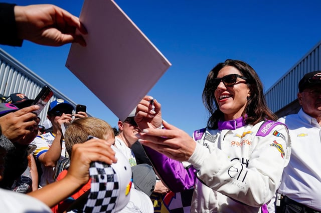 Katherine Legge signs autographs before the start of a NASCAR Cup Series at Phoenix Raceway, Sunday, March 9, 2025, in Avondale, Ariz. (AP Photo/Darryl Webb)