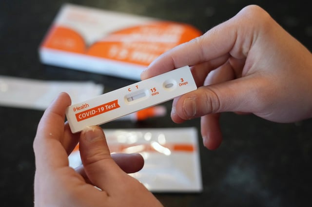 A Walmart worker shows she tested negative after using one of the new government-issued COVID-19 Antigen Rapid test kits she received to take a self-test while at home on February 8, 2022 in Provo, Utah. 