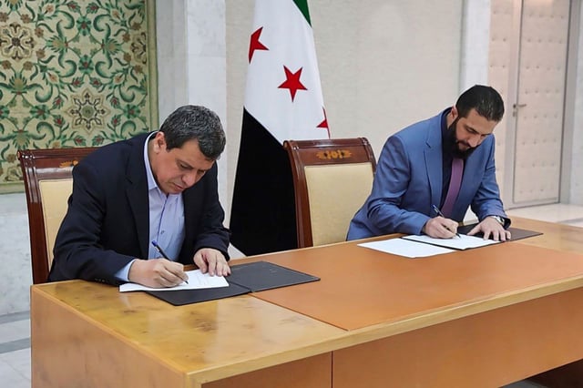 Syria's interim President Ahmad al-Sharaa, right, and Mazloum Abdi, the commander of Kurdish-led Syrian Democratic Forces, sign a deal in Damascus, Syria, on Monday.