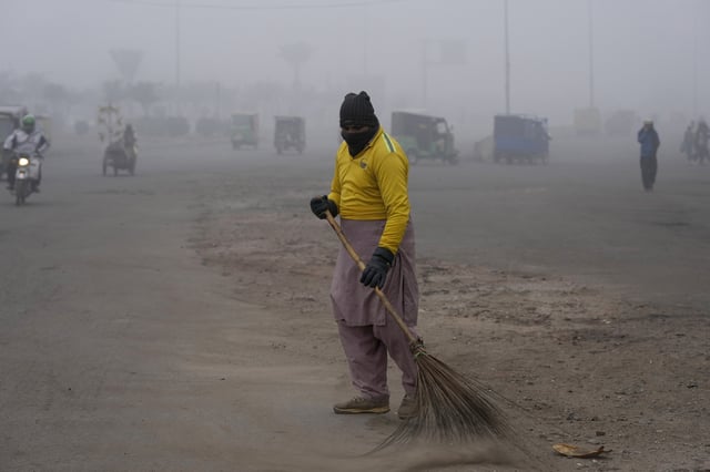 FILE - A sweeper cleans as smog envelops the area and reduces visibility in Lahore, Pakistan, Jan. 11, 2024. (AP Photo/K.M. Chaudary, File)
