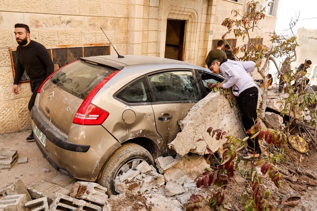 Palestinians stand near a damaged vehicle, near the site where a number of Palestinians were killed in an Israeli raid, in Jenin, in the Israeli-occupied West Bank, March 11, 2025. REUTERS/Raneen Sawafta