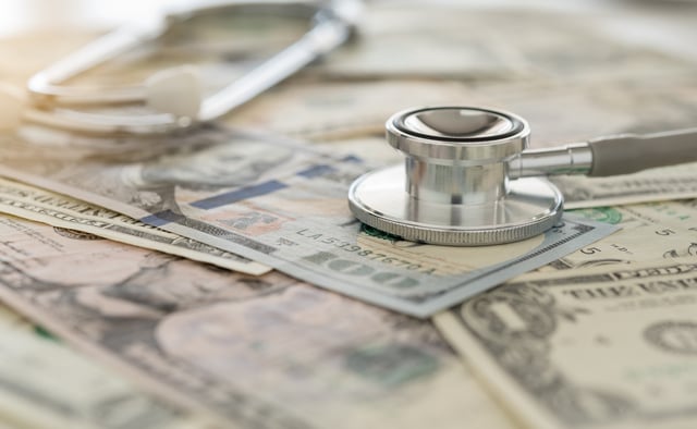 Stock image/file photo: A stethoscope laid over U.S. Dollar bills.