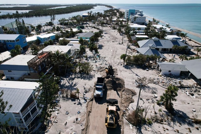Charlotte County workers clear feet of sand from a road on southern Manasota Key, in Englewood, Fla., following the passage of Hurricane Milton, Sunday, Oct. 13, 2024. (AP Photo/Rebecca Blackwell)