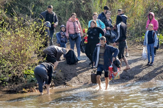 Des Syriens traversent la rivière Nahr al-Kabir, qui forme la frontière entre la province occidentale de Lattaquié en Syrie et le nord du Liban dans la région de Hekr al-Daher, le 11 mars 2025, alors que des familles de la minorité alaouite de Syrie entrent au Liban pour fuir la violence confessionnelle dans leur cœur le long de la côte méditerranéenne de la Syrie.
