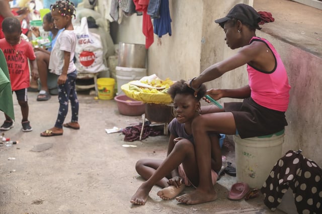 A woman combs the hair of a girl inside a shelter for people who have fled their home to escape gang violence in Port-au-Prince, Haiti, Friday, Feb. 28, 2025.(AP Photo/Odelyn Joseph)