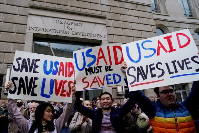 People hold placards, as the USAID building sits closed to employees after a memo was issued advising agency personnel to work remotely, in Washington, D.C., U.S., February 3, 2025. REUTERS/Kent Nishimura/File Photo