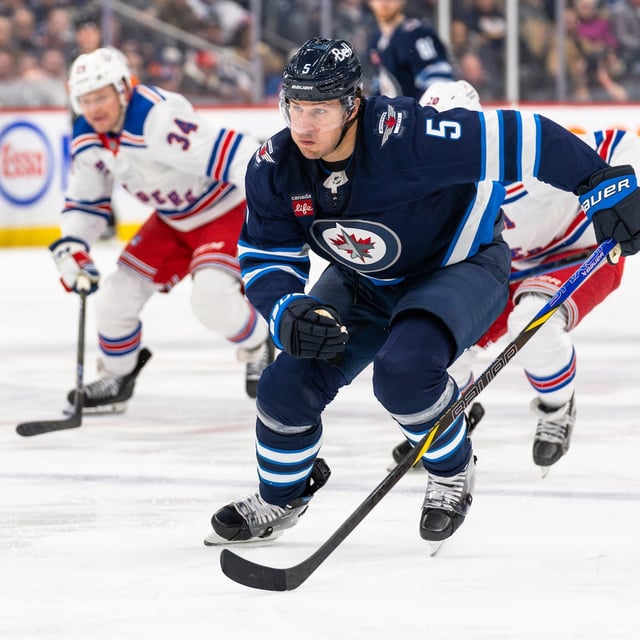 WINNIPEG, CANADA - MARCH 11: Luke Schenn #5 of the Winnipeg Jets races to the puck in the third period against the New York Rangers at Canada Life Centre on March 11, 2025 in Winnipeg, Canada. (Photo by Cameron Bartlett/Getty Images)
