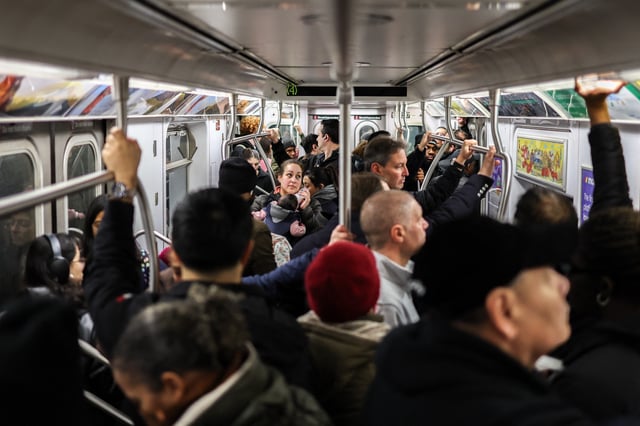 A woman feeds a baby while riding a packed subway train in the Manhattan borough of New York City on February 27, 2025.