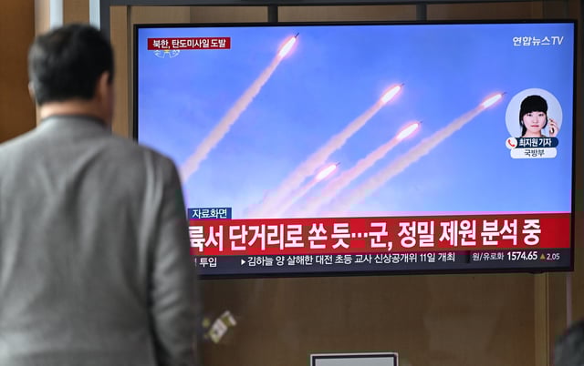 A man watches a television screen showing a news broadcast with file footage of a North Korean missile test, at a train station in Seoul on March 10.