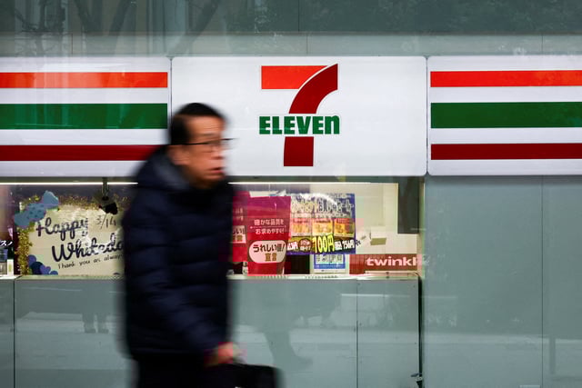A man walks past the logo of 7-Eleven displayed at their convenience store in Tokyo, Japan March 6, 2025. REUTERS/Issei Kato/File Photo