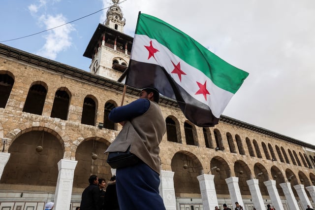 A person carries a flag adopted by the new Syrian rulers, in the Umayyad Mosque, after Syria's Bashar al-Assad was ousted, in Damascus, Syria, December 27, 2024. REUTERS/Amr Abdallah Dalsh/File Photo