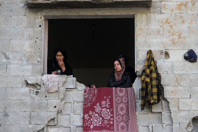 Palestinian women stand in a window of a damaged building, amid ceasefire negotiations with Israel, in Gaza City, January 15, 2025. REUTERS/Mahmoud Issa/File Photo