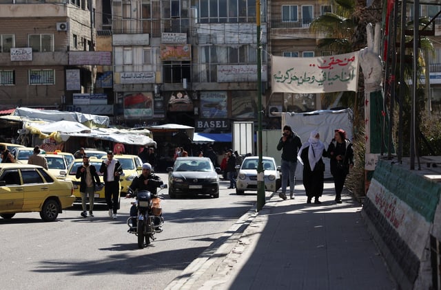 Cars drive and people walk along a street in Sweida, Syria February 25, 2025. REUTERS/Yamam al Shaar/File Photo