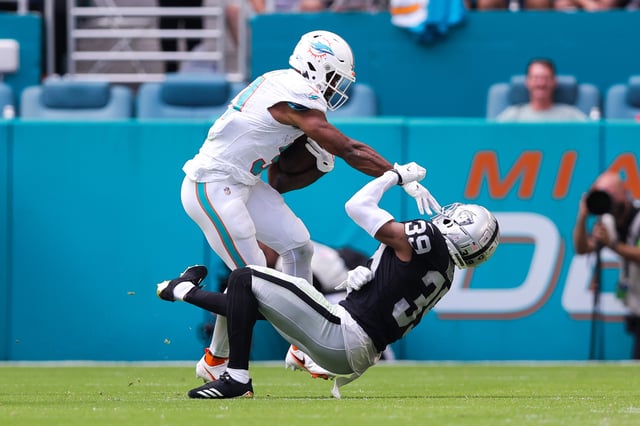 MIAMI GARDENS, FLORIDA - NOVEMBER 19: Raheem Mostert #31 of the Miami Dolphins stiff arms Nate Hobbs #39 of the Las Vegas Raiders during the second quarter of the game at Hard Rock Stadium on November 19, 2023 in Miami Gardens, Florida.