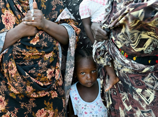 A child stands between two women at a school turned into a shelter, in Port Sudan, Sudan, August 29, 2024. REUTERS/Abrahim Mohammed Ishac/File Photo