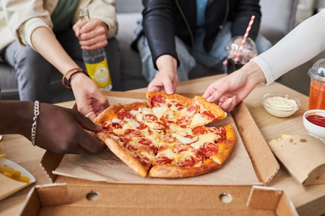Stock Image: Close up shot of hands taking slices of pepperoni pizza. Multiple restaurant chains are offering pizza deals on National Pi Day, on March 14, 2025.