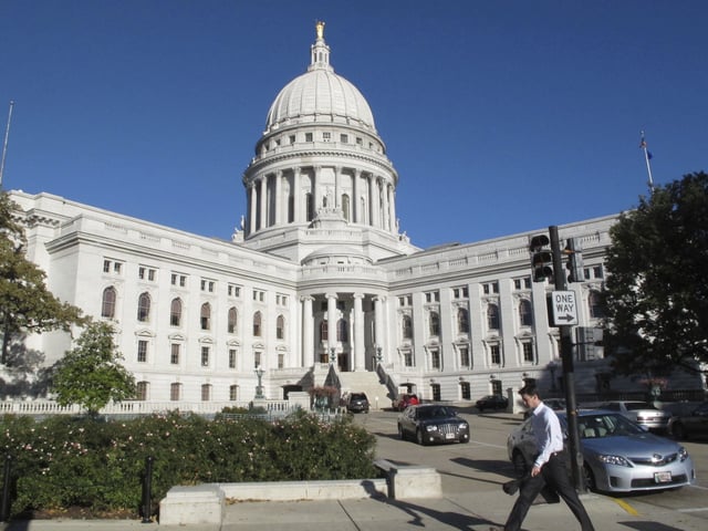 FILE - A man walks by the Wisconsin Capitol, Oct. 10, 2012, in Madison, Wis. (AP Photo/Scott Bauer, File)