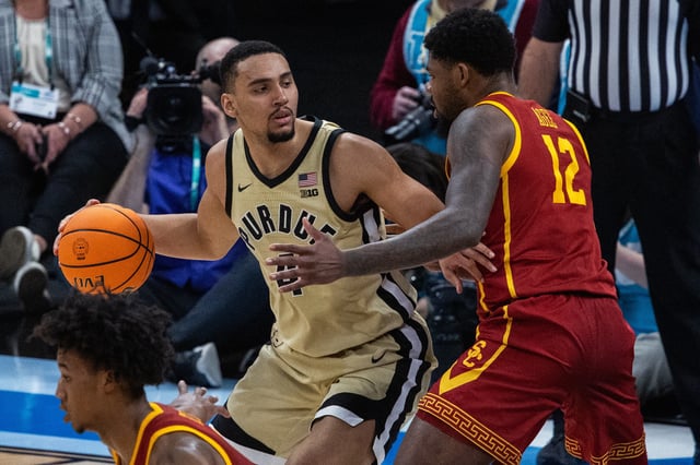 Mar 13, 2025; Indianapolis, IN, USA; Purdue Boilermakers forward Trey Kaufman-Renn (4) dribbles the ball while  USC Trojans forward Rashaun Agee (12) defends in the first half at Gainbridge Fieldhouse. Mandatory Credit: Trevor Ruszkowski-Imagn Images