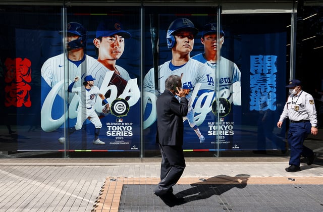 Baseball - Major League Baseball - Tokyo Series - Chicago Cubs Practice - Tokyo Dome, Tokyo, Japan - March 14, 2025 General view of a man walking past a Tokyo Series poster outside the stadium REUTERS/Issei Kato