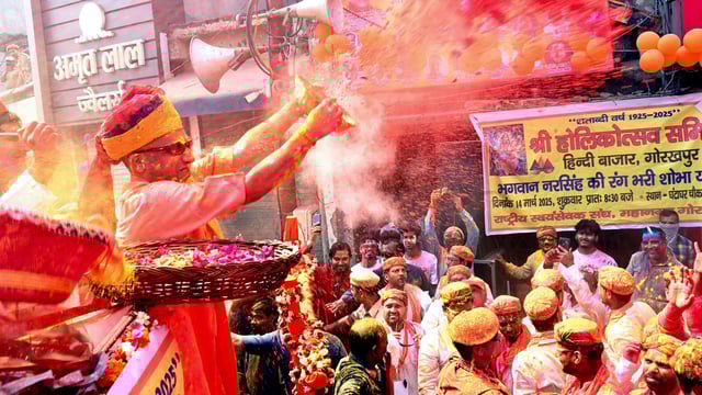 Uttar Pradesh Chief Minister Yogi Adityanath hurls coloured powder on people during a procession on the occasion of Holi, in Gorakhpur.