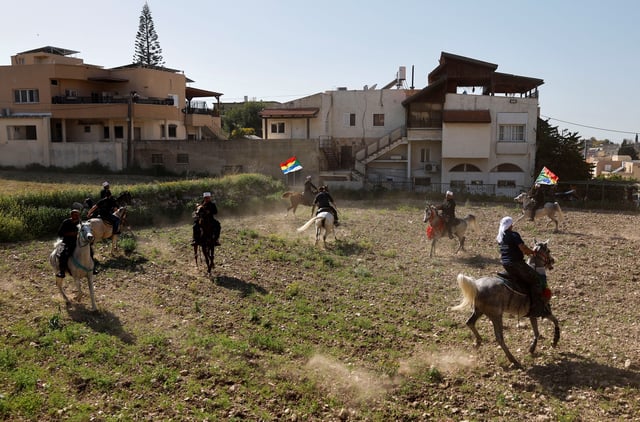 People ride horses and hold Druze flags on the day Israeli Druze leader Sheik Mowafaq Tarif and around 100 Syrian Druze religious elders, in the first Druze delegation from Syria just after 1973 war, visit the Nabi Shuayb Shrine, a holy place for the Druze community, in northern Israel March 14, 2025. REUTERS/Ammar Awad