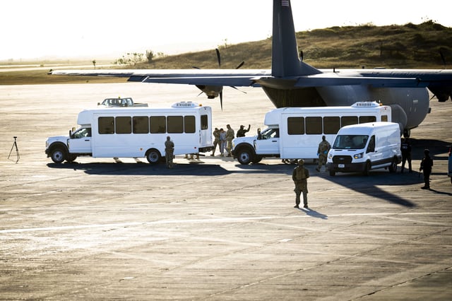 In this photo reviewed by the US military, security forces lead a man in gray sweatsuit away from a a military cargo plane that transported deportees from El Paso, Texas, to Guantánamo Bay, Cuba, on February 7.