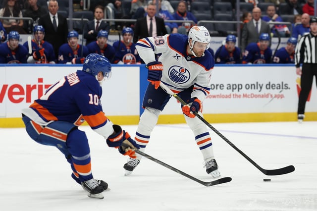 Mar 14, 2025; Elmont, New York, USA; Edmonton Oilers center Leon Draisaitl (29) skates with the puck while New York Islanders right wing Simon Holmstrom (10) defends during the third period at UBS Arena. Mandatory Credit: Thomas Salus-Imagn Images