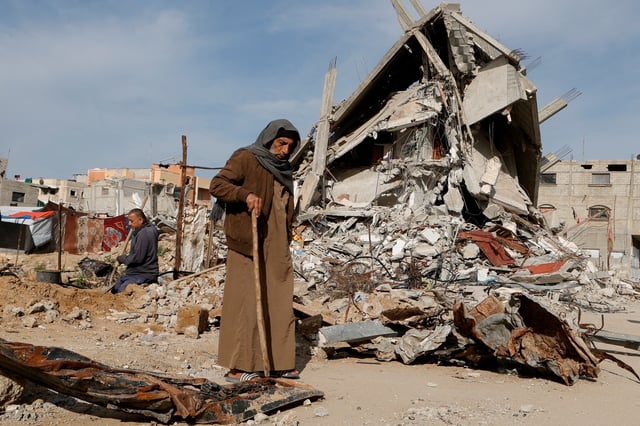 A Palestinian man walks near rubble of houses destroyed during the Israeli offensive, in Rafah, in the southern Gaza Strip, March 13, 2025. REUTERS/Hatem Khaled/File Photo