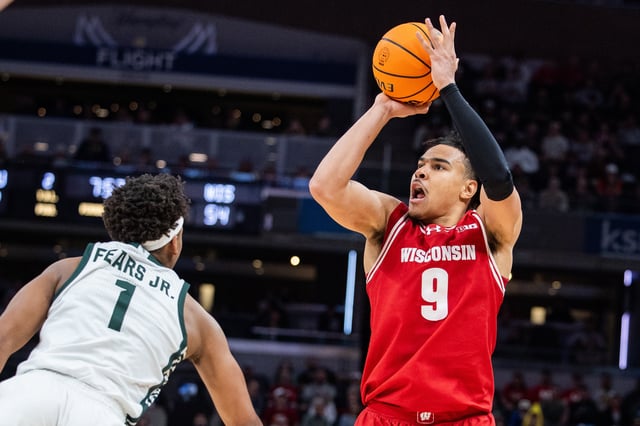 Mar 15, 2025; Indianapolis, IN, USA; Wisconsin Badgers guard John Tonje (9) shoots the ball while Michigan State Spartans guard Jeremy Fears Jr. (1) defends in the second half  at Gainbridge Fieldhouse. Mandatory Credit: Trevor Ruszkowski-Imagn Images