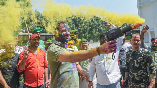 Rashtriya Janata Dal (RJD) MLA Tej Pratap shoots hues in the air while celebrating Holi with party workers at his residence, in Patna on Saturday. (ANI Photo)