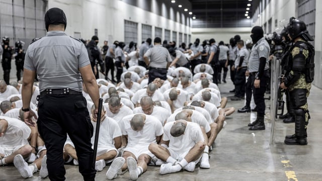 A prison guard transfers deportees from the U.S., alleged to be Venezuelan gang members, to the Terrorism Confinement Center in Tecoluca, El Salvador, Sunday, March 16, 2025.