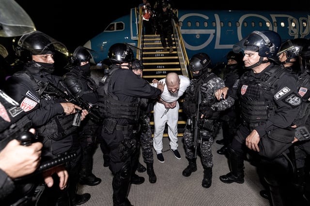 Salvadoran police officers escort alleged members of the Venezuelan gang Tren de Aragua recently deported by the U.S. government to be imprisoned in the Terrorism Confinement Center (CECOT) prison, as part of an agreement with the Salvadoran government, at the El Salvador International Airport in San Luis Talpa, El Salvador, in this handout image obtained March 16, 2025. Secretaria de Prensa de la Presidencia/Handout via REUTERS