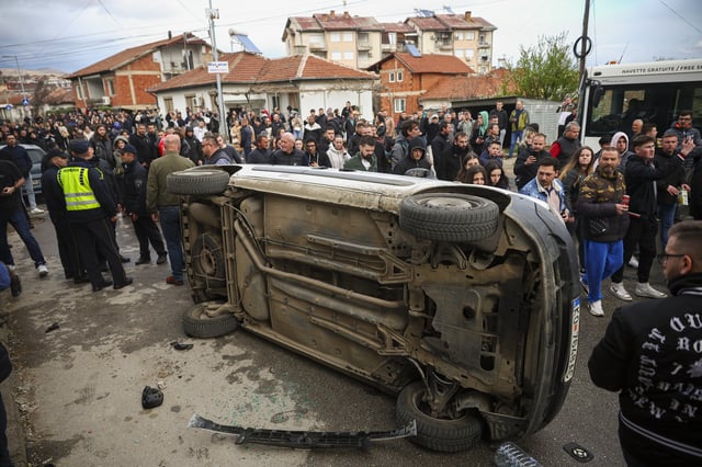 A vehicle is overturned by people protesting near the home of the owner of a nightclub that was the scene of a massive fire, after a vigil for the victims in the town of Kocani, North Macedonia, Monday, March 17, 2025. (AP Photo/Armin Durgut)